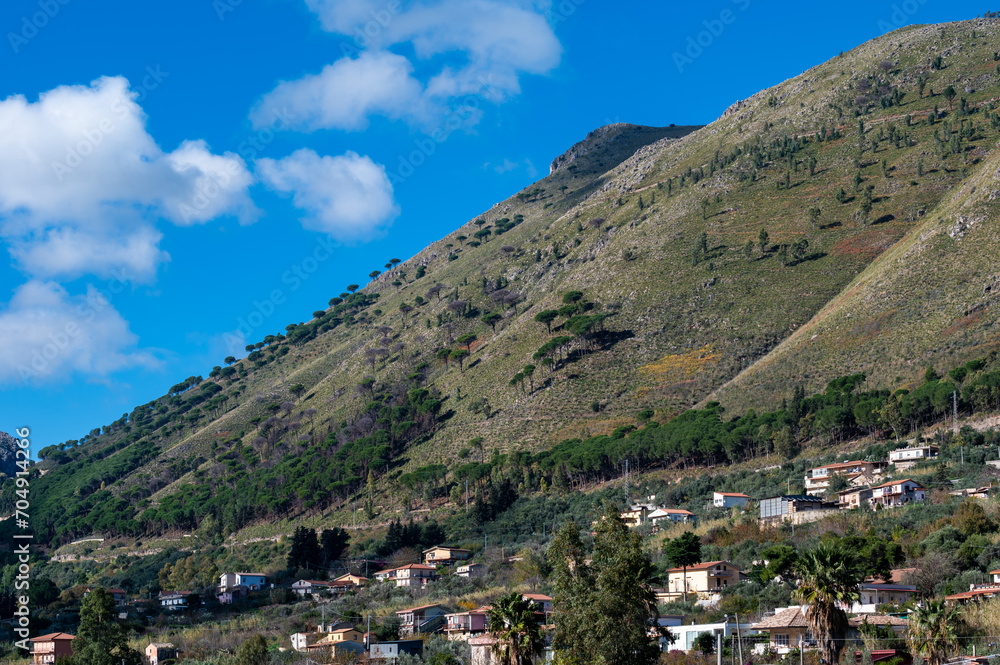 Panoramic view over the rough mountains with houses and blue sky around Cannizaro- Favare, Italy