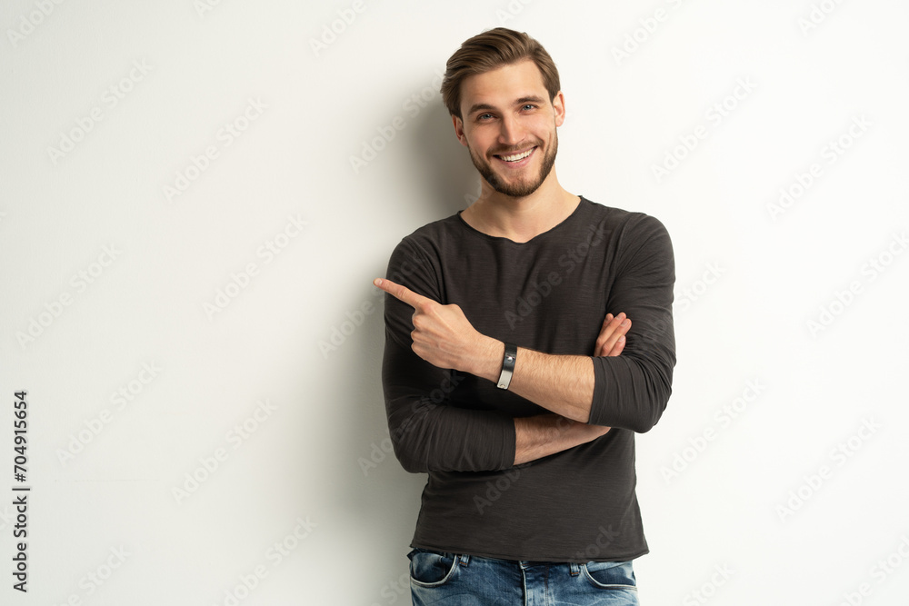 Positive young man pointing aside with fingers hand gesture at copy space advertising product, presenting sale discount standing isolated on white Positive young man pointing aside with fingers hand gesture at copy space advertising product, presenting sale discount standing isolated on white