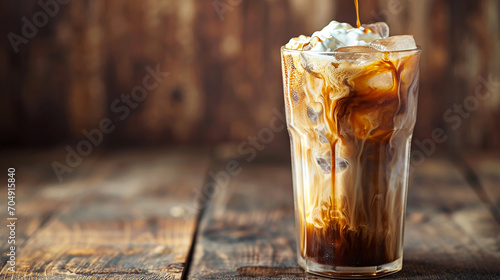 Iced coffee in a tall glass with cream poured over. Wood background. Made with generative ai