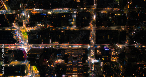 Top Down Aerial View of New York City Streets Lit with Neon Lights from Billboards. Busy Metropolis Traffic with Cars, Yellow Taxis, Commercial Vehicles and People Walking