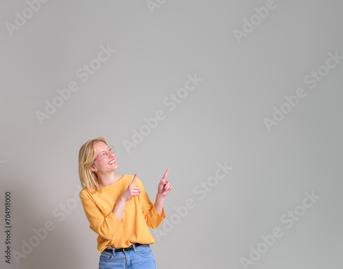 Happy young saleswoman with blond hair pointing at copy space and marketing against white background