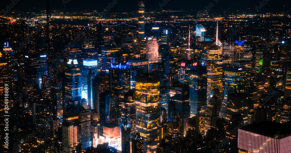 Fototapeta premium Aerial Image of Office Buildings at Night. Rooms Have Lights On, Businesspeople and Managers Working Long Hours in New York City. Helicopter Cityscape View of Manhattan in the Evening