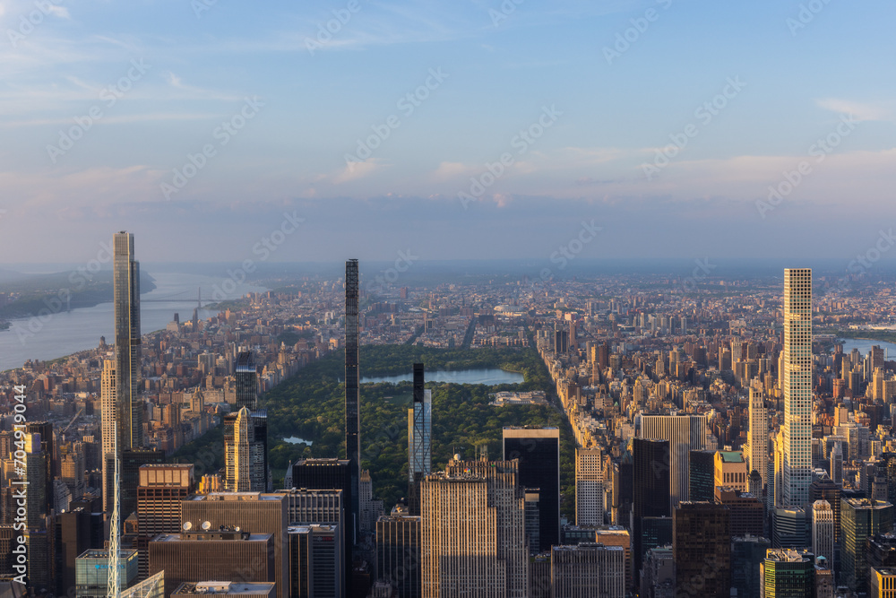 New York Cityscape at Sunset. Aerial Photo from a Helicopter. Modern Skyscraper Buildings Around Central Park in Manhattan Island. Focus on Nature, Trees and Lakes in the Park in the City