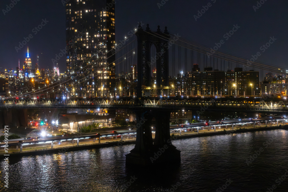 Fototapeta premium Iconic New York City Landscape Over East River with Skyscrapers, Brooklyn Bridge, Cars and Ferry Boats. Cinematic Night Urban Skyline