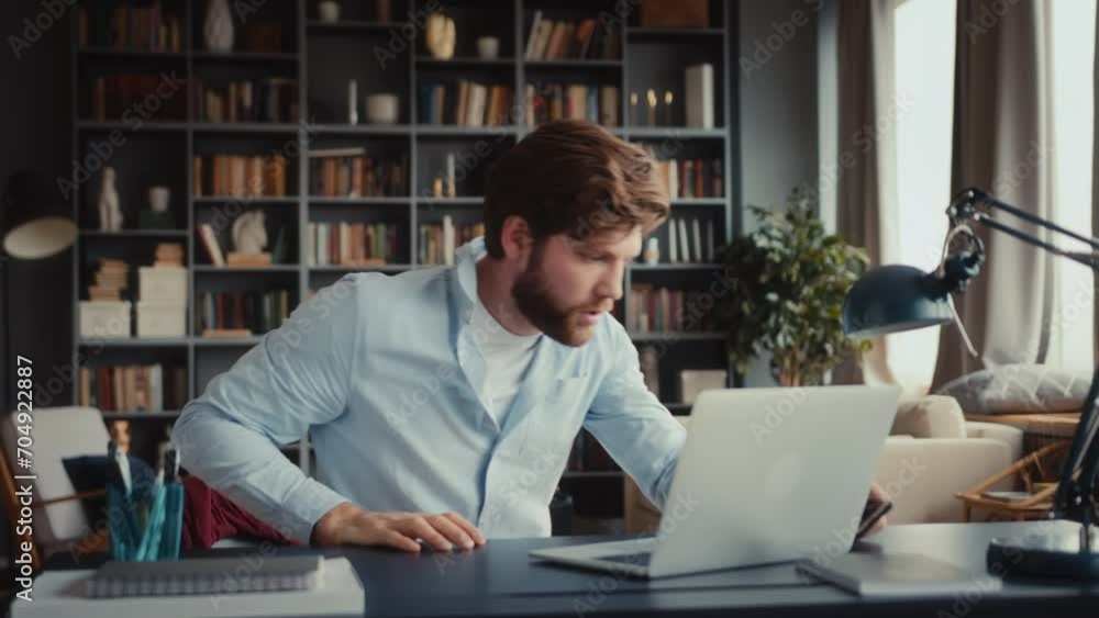 young man with beard in blue shirt sits at table in home office with feet on desk sleeping. wakes up in panic, checks time, takes clothes, hurry to quit and run away being late young man with beard in blue shirt sits at table in home office with feet on desk sleeping. wakes up in panic, checks time, takes clothes, hurry to quit and run away being late