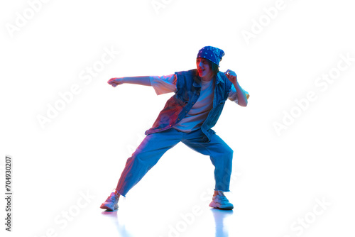 Young girl in sport style casual clothes dancing dace hall, hip hop isolated over white background in neon light. Concept of contemporary dance, street style, youth, hobby, action, lifestyle