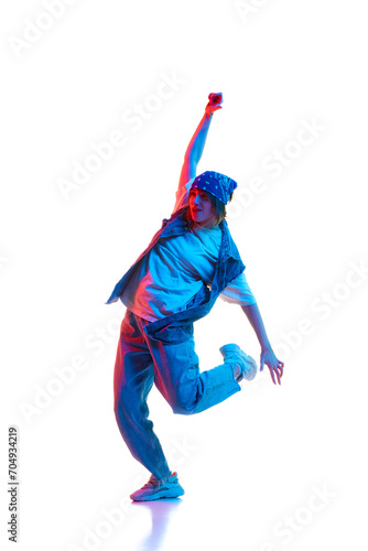 Cheerful, positive young woman in casual clothes dancing hip hop isolated over white background in neon light. Concept of contemporary dance, street style, youth, hobby, action, lifestyle
