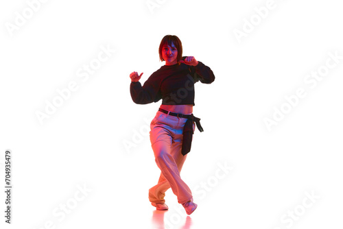 Active young girl in casual clothes dancing hip hop, dance hall isolated over white background in neon light. Concept of contemporary dance, street style, youth, hobby, action, lifestyle