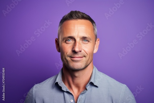 Portrait of a handsome middle-aged man on a purple background. © Inigo
