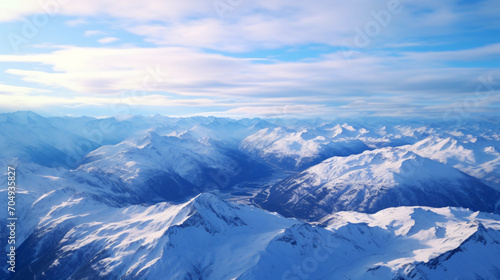 Aerial shot of a serene mountain range with snow-capped peaks and valleys. © Thomas