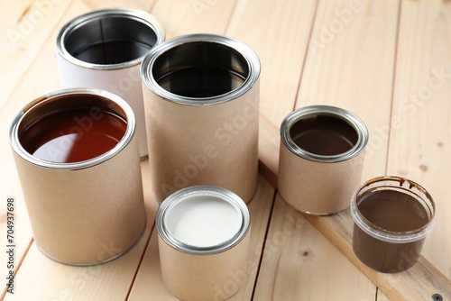 Cans with different wood stains and varnish on wooden surface
