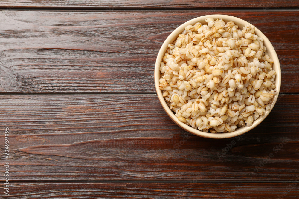 Delicious pearl barley in bowl on wooden table, top view. Space for text Delicious pearl barley in bowl on wooden table, top view. Space for text
