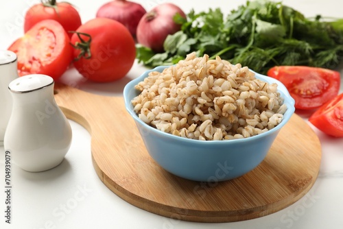 Delicious pearl barley in bowl served on white table