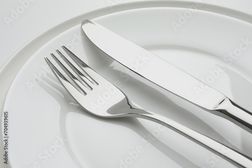 Clean plates, fork and knife on white background, closeup