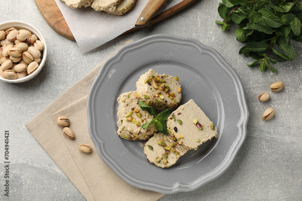 Tasty halva with pistachios and mint on light grey table, flat lay