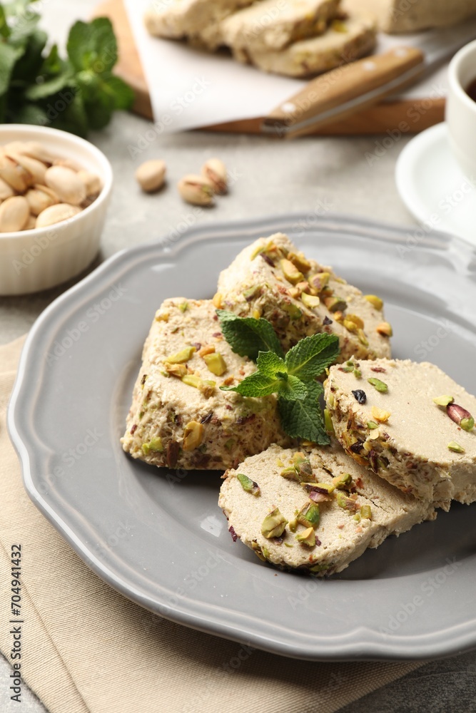 Tasty halva with pistachios and mint on table, closeup