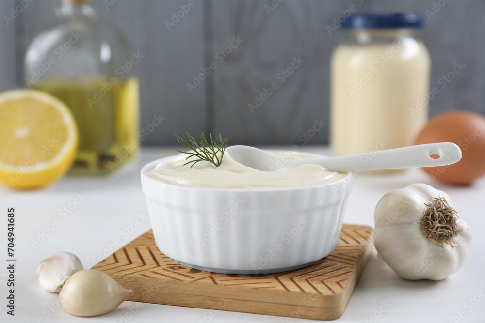 Fresh mayonnaise sauce in bowl and ingredients on white table Fresh mayonnaise sauce in bowl and ingredients on white table