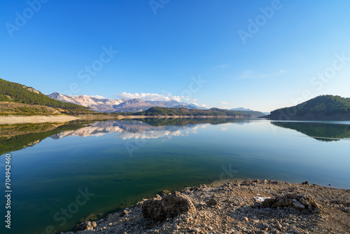 Reflection of trees and green leaves in the lake water. Liquidambar orientalis protected area in Burdur Turkey. Karacaoren ( barrage ) dam lake. Panorama.