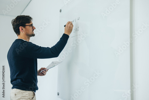 Business man writing financial figures on a white board during a meeting photo