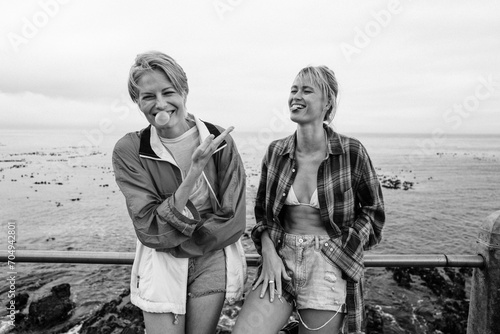 Two happy friends blowing bubble gum by the sea photo