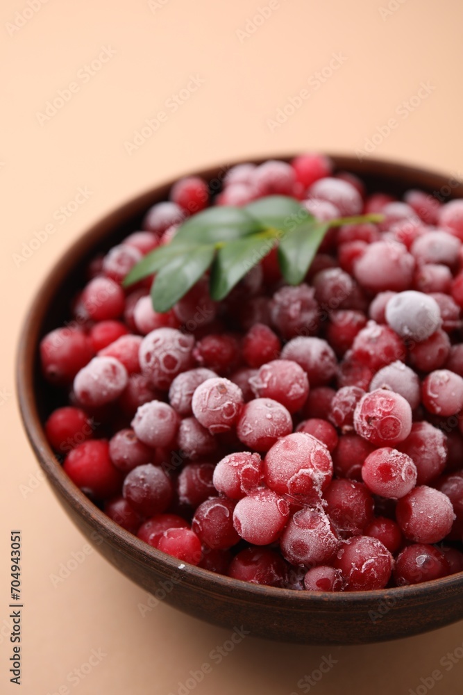 Frozen red cranberries and green leaves on beige background, closeup Frozen red cranberries and green leaves on beige background, closeup