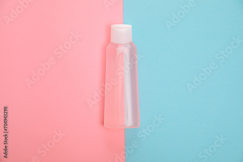Blank transparent cosmetic bottle on pink and blue background. Branding mock-up for lotion, cream, gel, foam, soap or shampoo. Symmetrical composition. Beauty blogger concept.