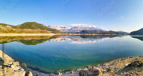 Reflection of trees and green leaves in the lake water. Liquidambar orientalis protected area in Burdur Turkey. Karacaoren ( barrage ) dam lake. Panorama.