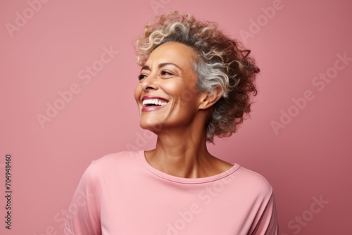 Portrait of a happy senior woman with curly hair over pink background