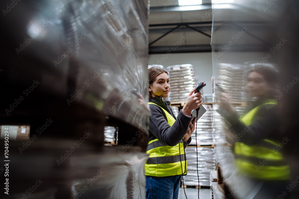 Female warehouse worker holding scanner, scanning the barcodes on ...