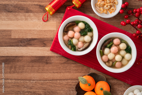 Eating red and white small tangyuan with savory soup and vegetable for lunar new year festival.