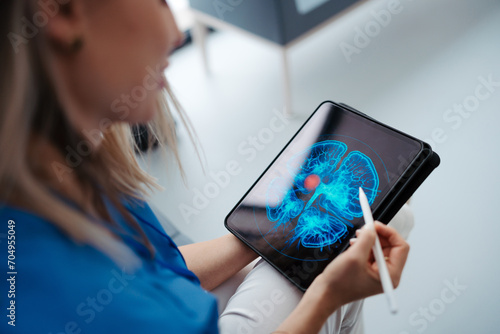 фотографія Portrait of female doctor sitting in office, looking at test results CT scans in tablet