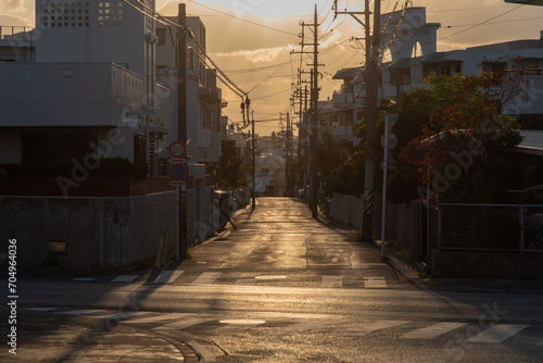 正面に太陽のある夕焼けの街の直線の道