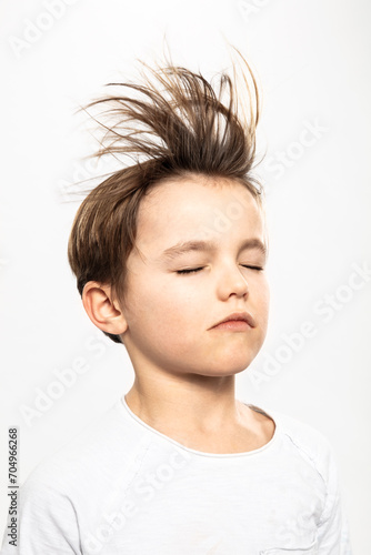 Junge im Studio weiss angezogen mit fliegenden Haaren photo