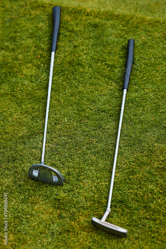 Vertical photo. Two golf clubs on the green grass. Professional sports for rich people.