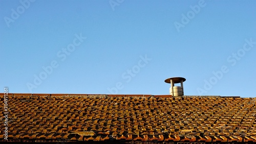 weathered roof with chimney against the sky