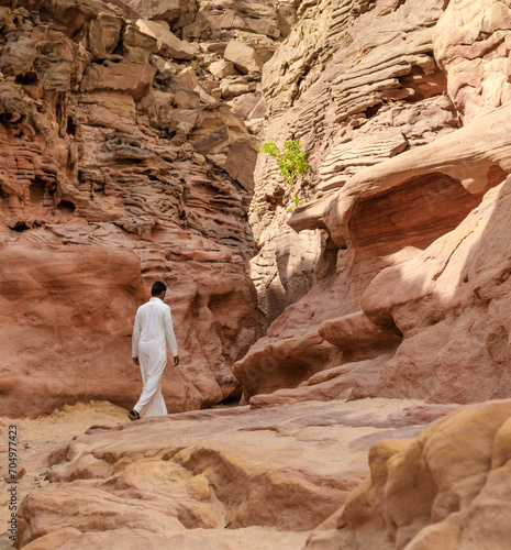 man in white arab clothing walks in a colored canyon in Egypt Dahab South Sinai