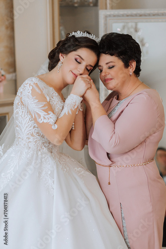 A beautiful and happy mother and her daughter, the bride, are standing next to each other. The best day for parents. Tender moments at the wedding.