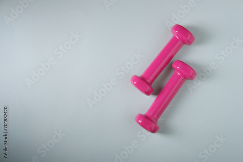 Small pink dumbbells on a blue background, top view, place for the inscription