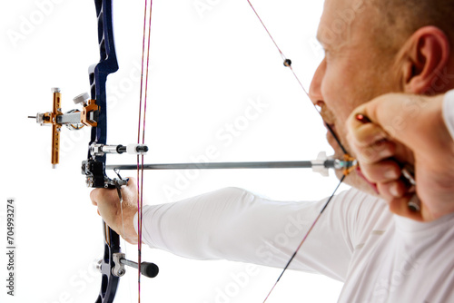Close-up of man, archery athlete aiming with artery bow on target isolated over white studio background. Concept of professional sport and hobby, competition, action, game