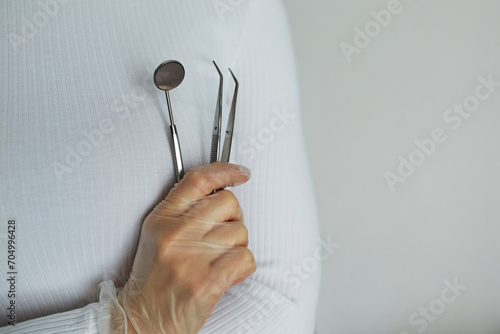 Dentist tools in gloved hand. Close-up with a doctor in the background