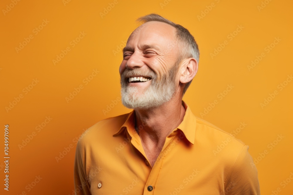 Portrait of a smiling senior man in yellow shirt on orange background Portrait of a smiling senior man in yellow shirt on orange background