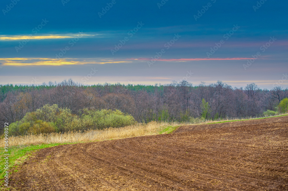 Witness a stunning sunset over a plowed field Experience the beauty of nature's colors unfolding Capture a picturesque backdrop for your enjoyment