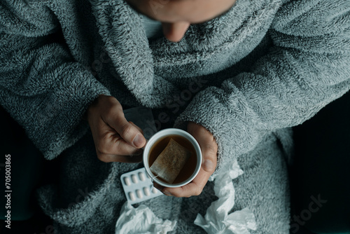 ill man in a robe warming up with a cup of tea