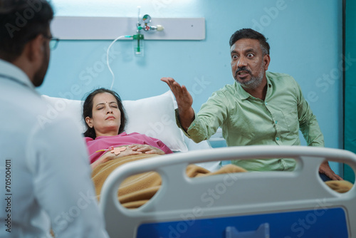 Shoulder shot, angry patient husband scolding or arguing with doctor at hospital ward - concept of emergency, communication problems and dispute photo