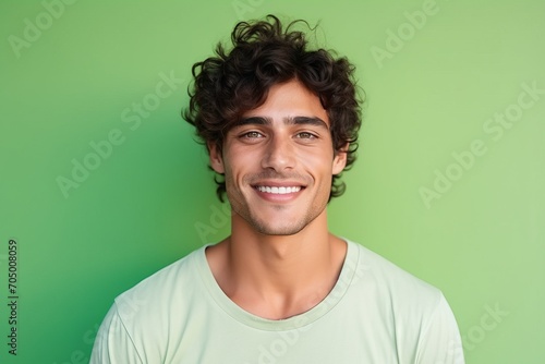 Portrait of handsome young man with curly hair against green background.