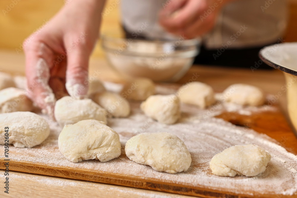 A woman forms pieces of dough for making donuts. The process of making donuts