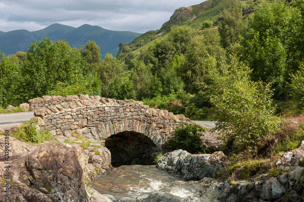 Ashness Bridge, a traditional packhorse bridge  over Barrow Beck, Borrowdale, with Skiddaw in the distance: Lake District, Cumbria, UK