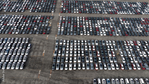 Aerial view of a new car lot, neatly arranged vehicles reflecting uniformity and precision, symbolizing organized commerce and transportation.