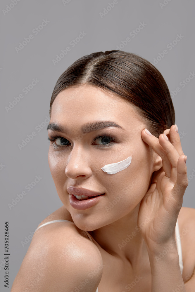 Beautiful Woman Face Skin Care. Portrait Of Attractive Young Female Applying Cosmetics Cream .
