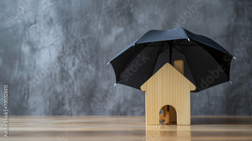 Small Wooden House under Umbrella for Home Insurance Concept on Table with Gray Background © Nico Vincentini